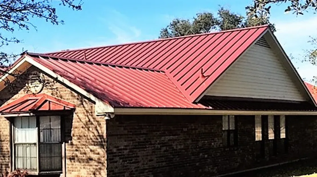 Roof repair on a red metal residential roof